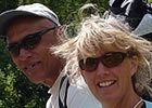 A man, woman, and child look at the camera while sitting on a mountain trail.