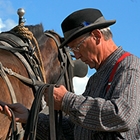 A man stands in heritage clothing by his horse at Fort Steele