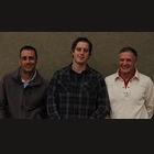 three men standing behind a large poster of a new home
