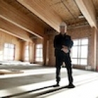 A man in a hard-hat stands proudly in  the construction of the Elkford CommunityCentre project.