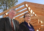 Two men and one woman in front of timber-frame structure