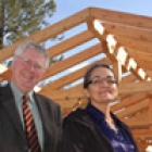 Two men and one woman in front of timber-frame structure