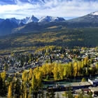 The small town of Golden, interspersed with greenery, is set against a blue and white mountain backdrop.