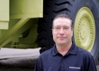A man stands in front of a giant dump truck