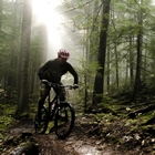 A man rides down a muddy trail surrounded by fresh mud and a soft light.