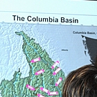 Three people stare at a map of the Columbia Basin.