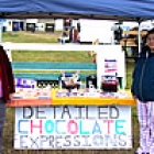 two ladies standing beside a chocolate stand