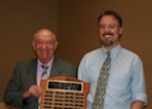 Two men hold an award