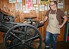 Man standing beside an old-fashioned letterpress machine in Fernie, BC