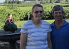 an older couple stand in front of a cherry orchard