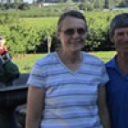 an older couple stand in front of a cherry orchard