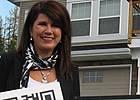 woman standing by a house holding up a QR code sign