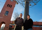 a man and woman near a tree sculpture and clock tower