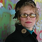 Portrait of a woman with curly hair and eccentric clothing.