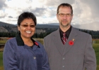 A woman and a man stand with mountains in the background