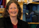 lady sitting at a wooden loom smiling