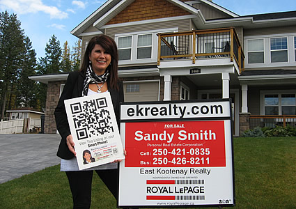 woman standing by a house holding up a QR code sign