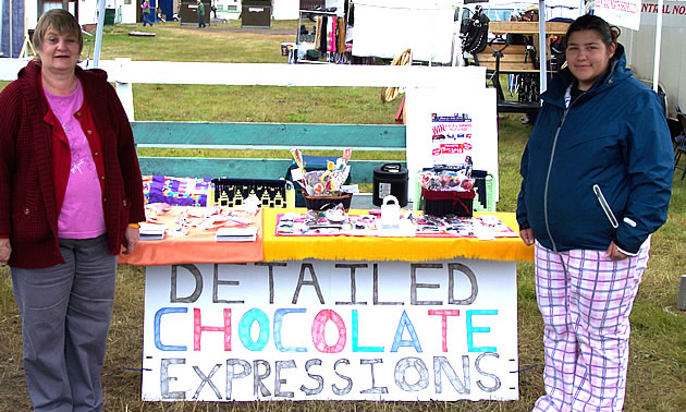 two ladies standing beside a chocolate stand