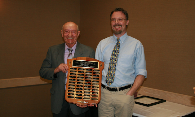 Two men hold an award