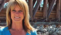 Golden's mayor, Christina Benty, stands in front of a bridge over a river
