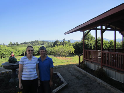 an older couple stand in front of a cherry orchard