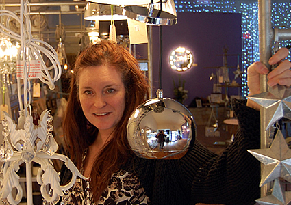 lady standing next to lighting and furniture pieces