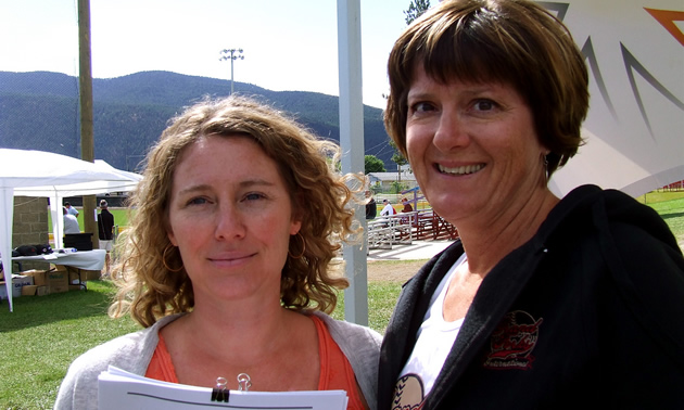 Two ladies standing side by side with paperwork in their hands