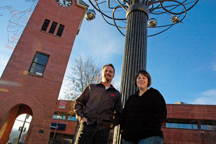 a man and woman near a tree sculpture and clock tower