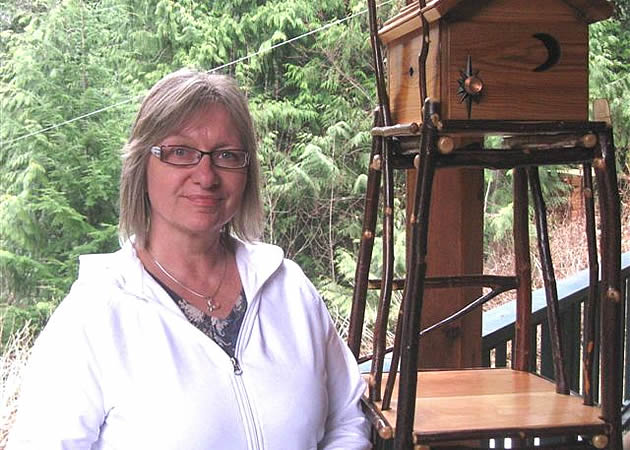 woman standing next to a home made bird house