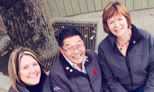 A woman, man and woman sitting side by side. 