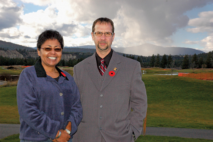 A woman and a man stand with mountains in the background